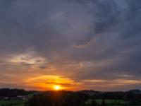 Kleinere Wolkengruppen beginnen vom Sonnenuntergang zu leuchten